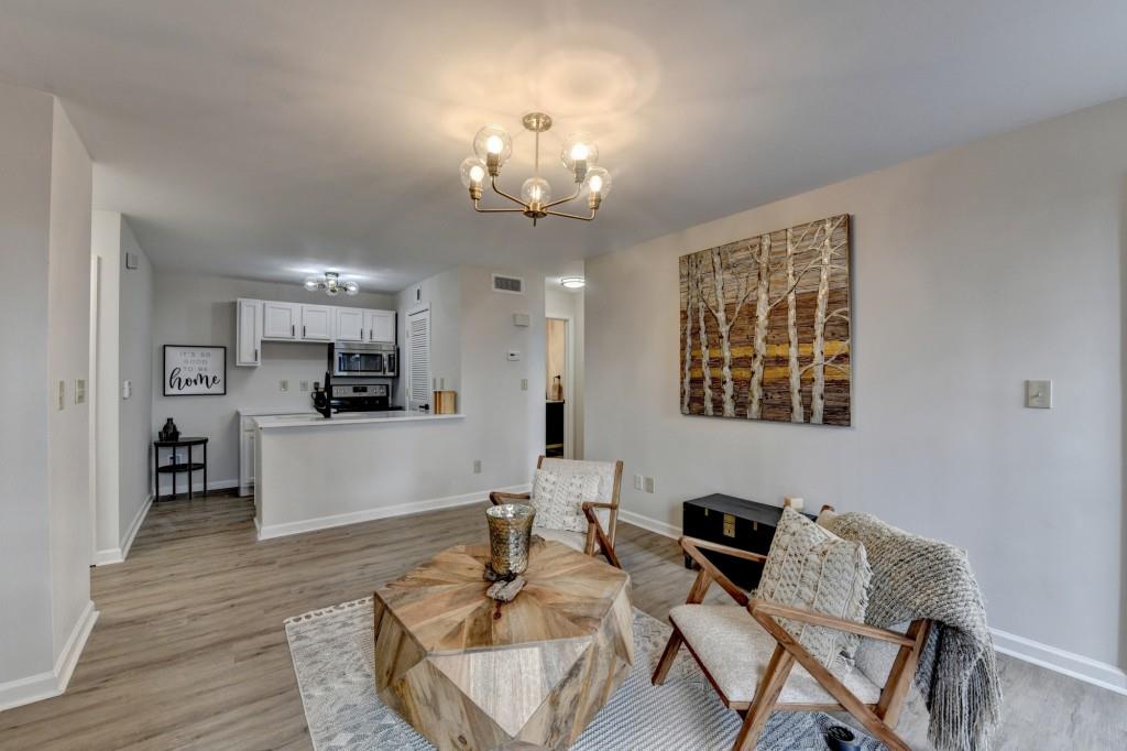 a living room with furniture kitchen view and a chandelier