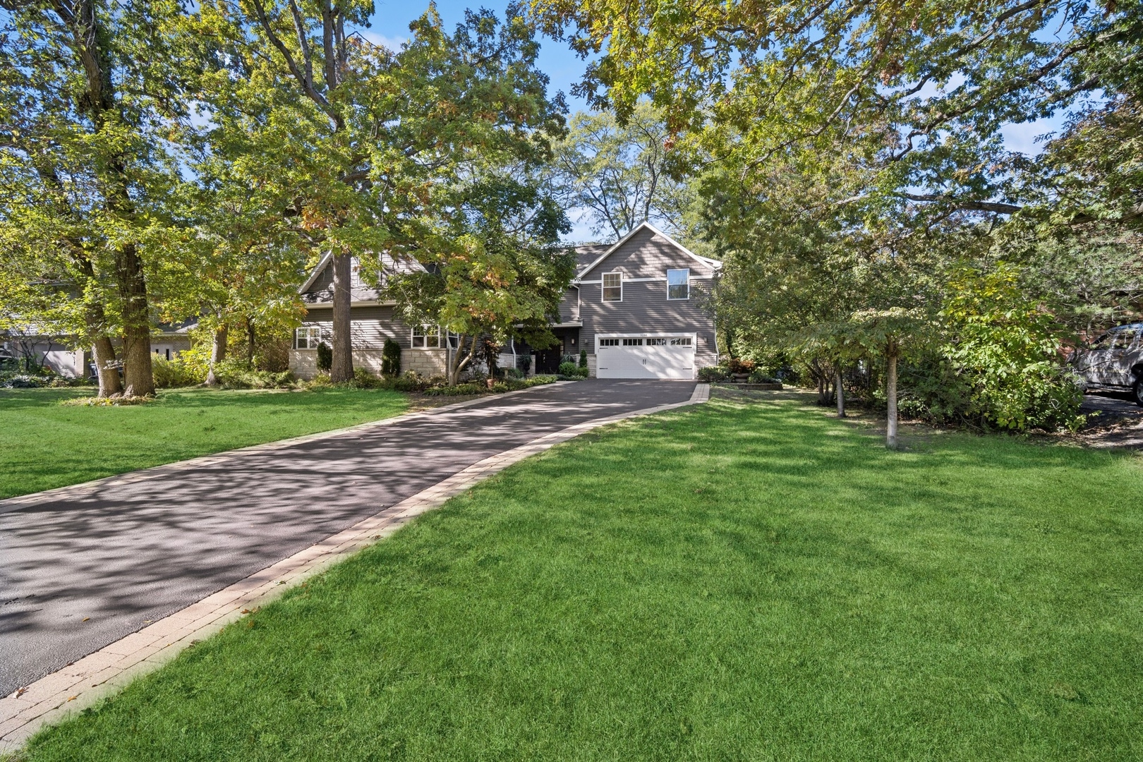 a pathway of a house with a big yard and large trees