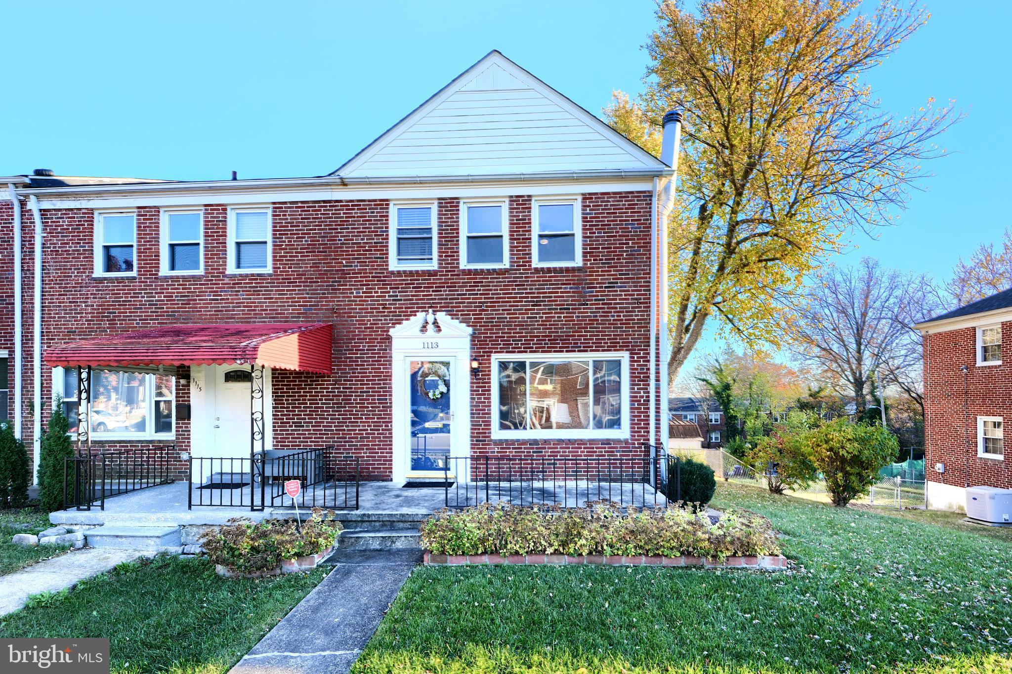 a view of a brick house with a yard plants and a table and chairs