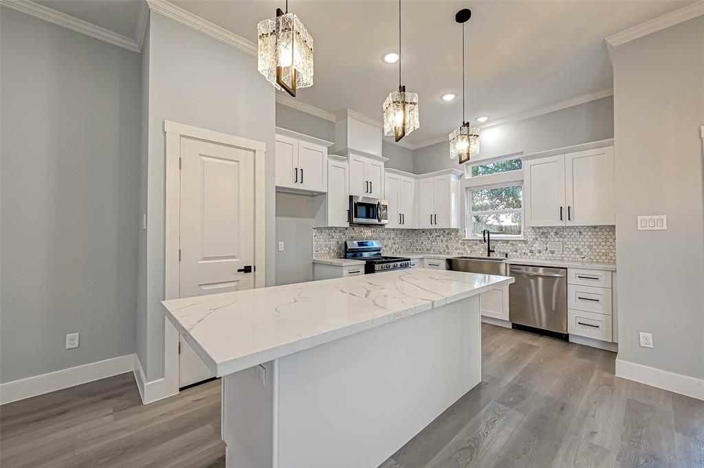 a large white kitchen with lots of counter space wooden floor and stainless steel appliances