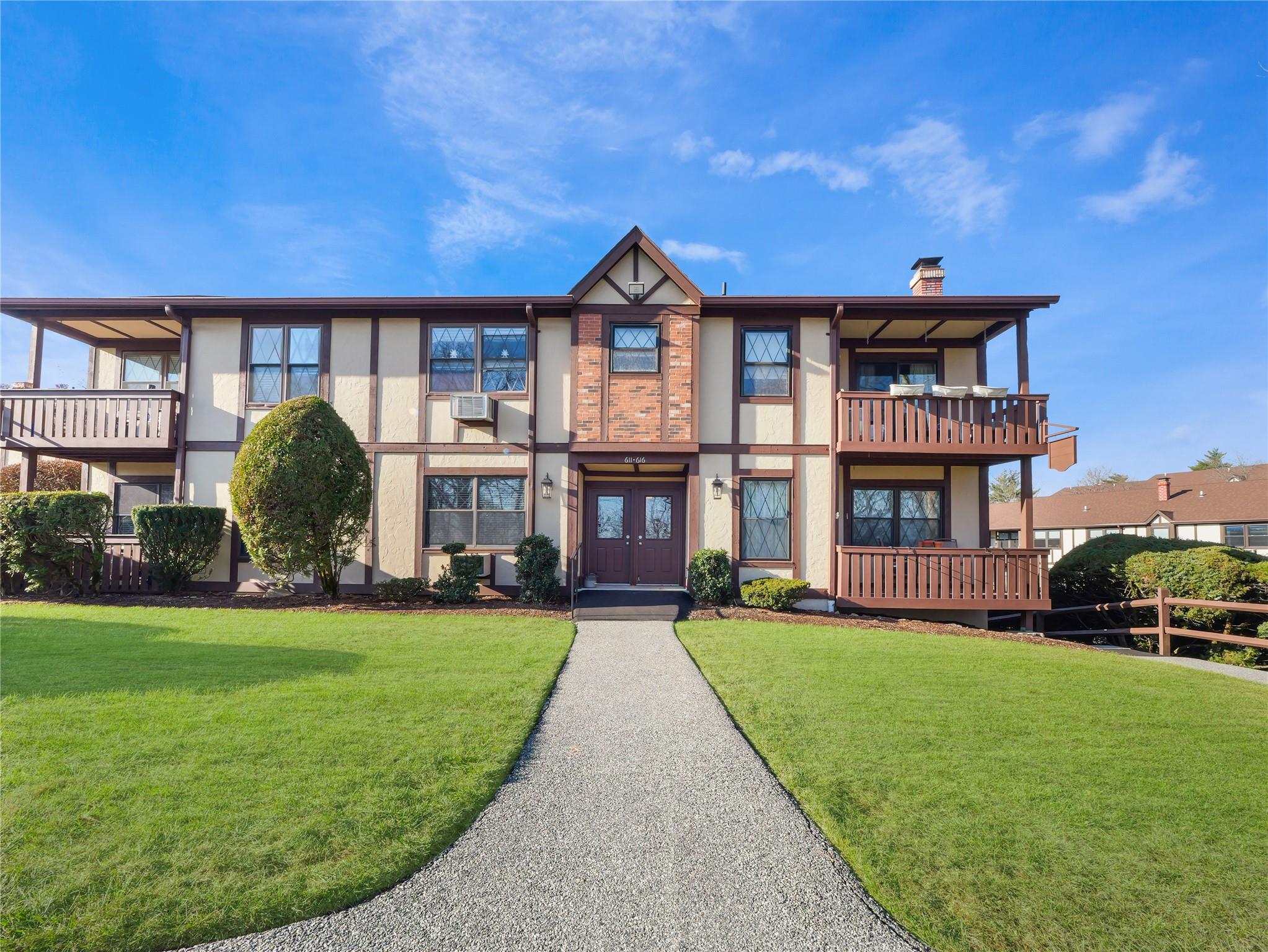 View of front of home featuring a balcony and a front lawn