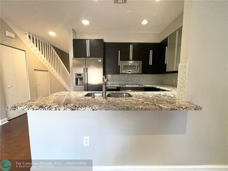 a kitchen with kitchen island granite countertop a sink and cabinets