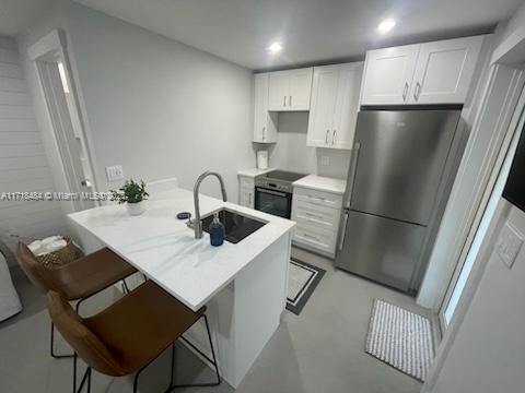 a kitchen with stainless steel appliances a refrigerator a sink a stove a table and chairs