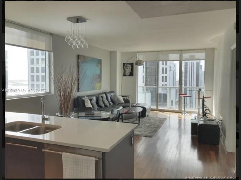 a kitchen with a sink dishwasher a stove and a dining table with wooden floor