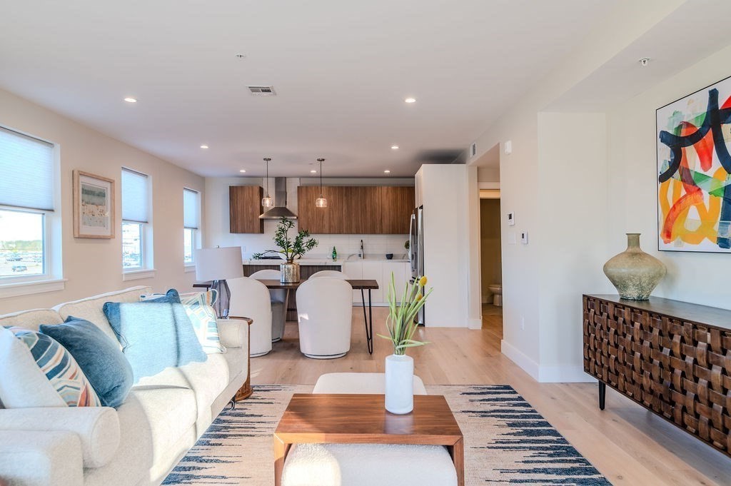 a living room with a couch and a dining table with wooden floor