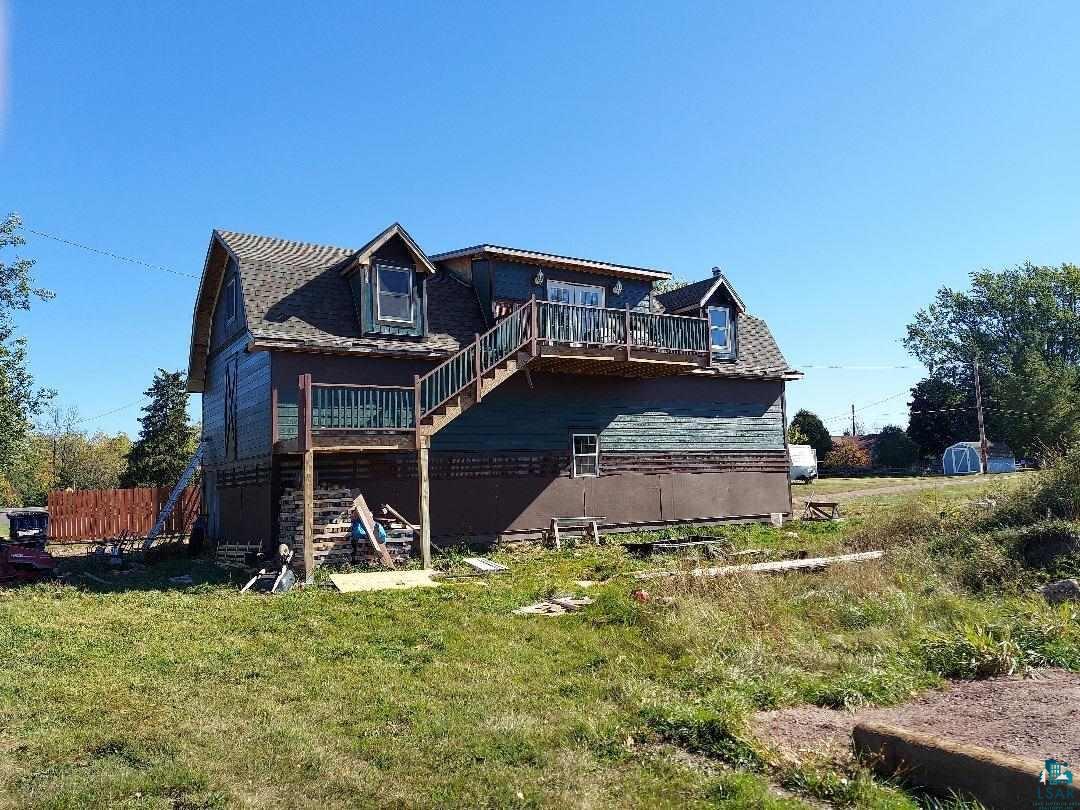 Back of house with a wooden deck and a yard