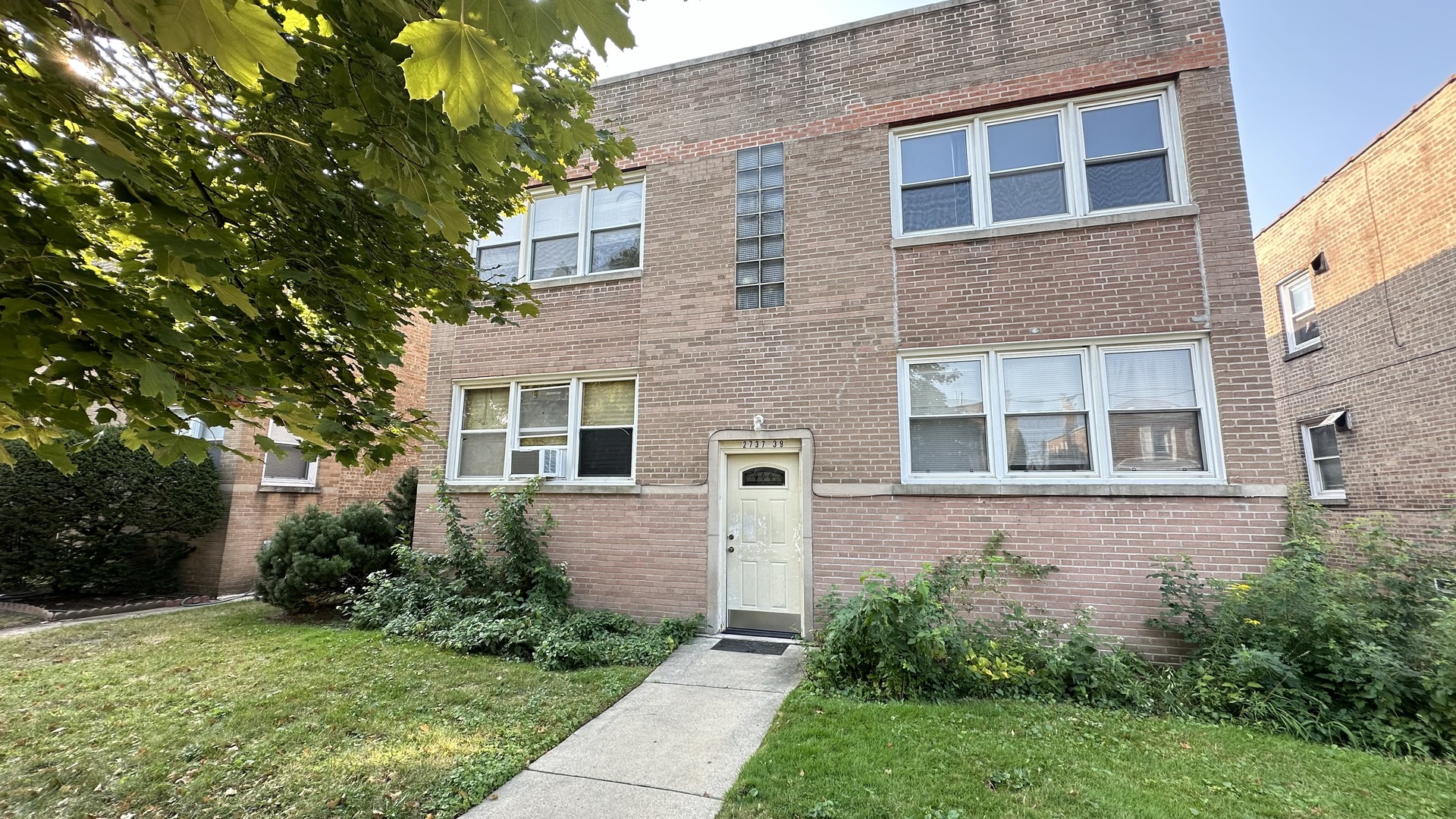 a view of a brick house with a yard and plants