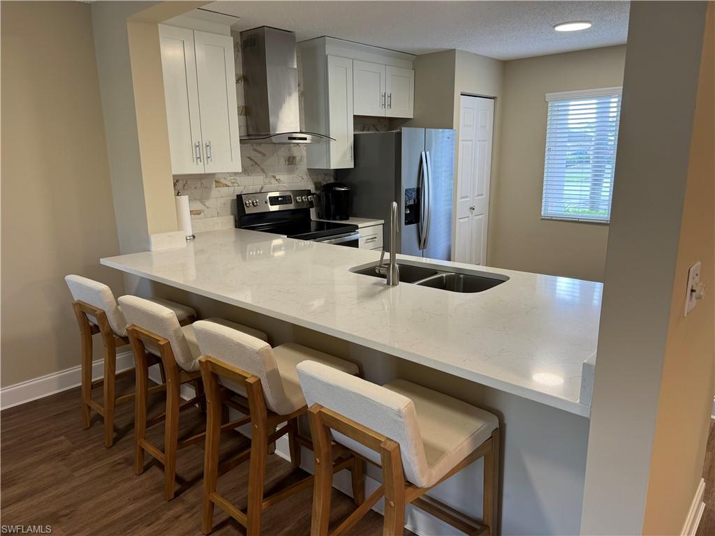 Open Kitchen with a bar and stainless steel appliances, and white cabinetry