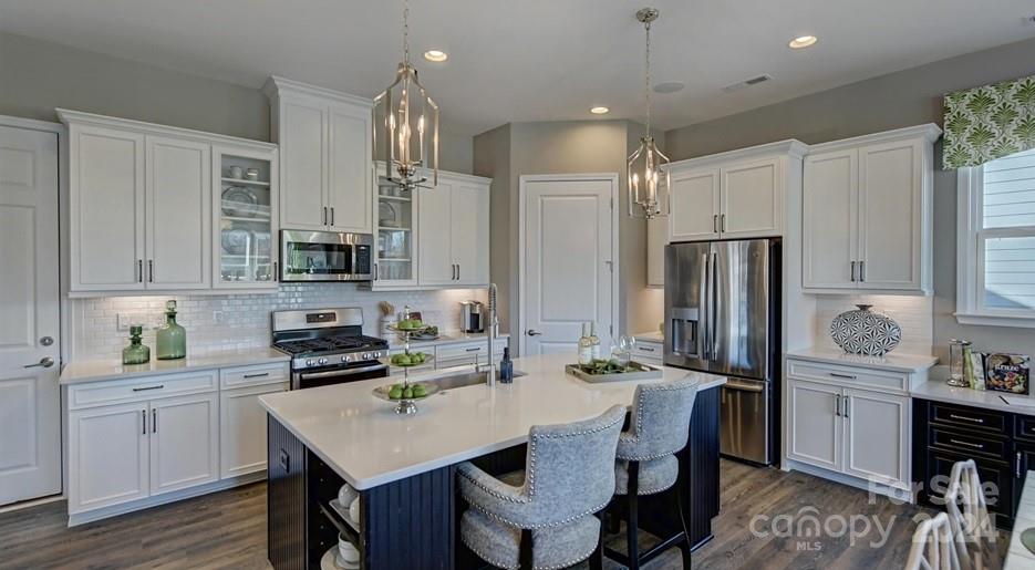 a kitchen with stainless steel appliances a sink a stove a refrigerator cabinets and a dining table