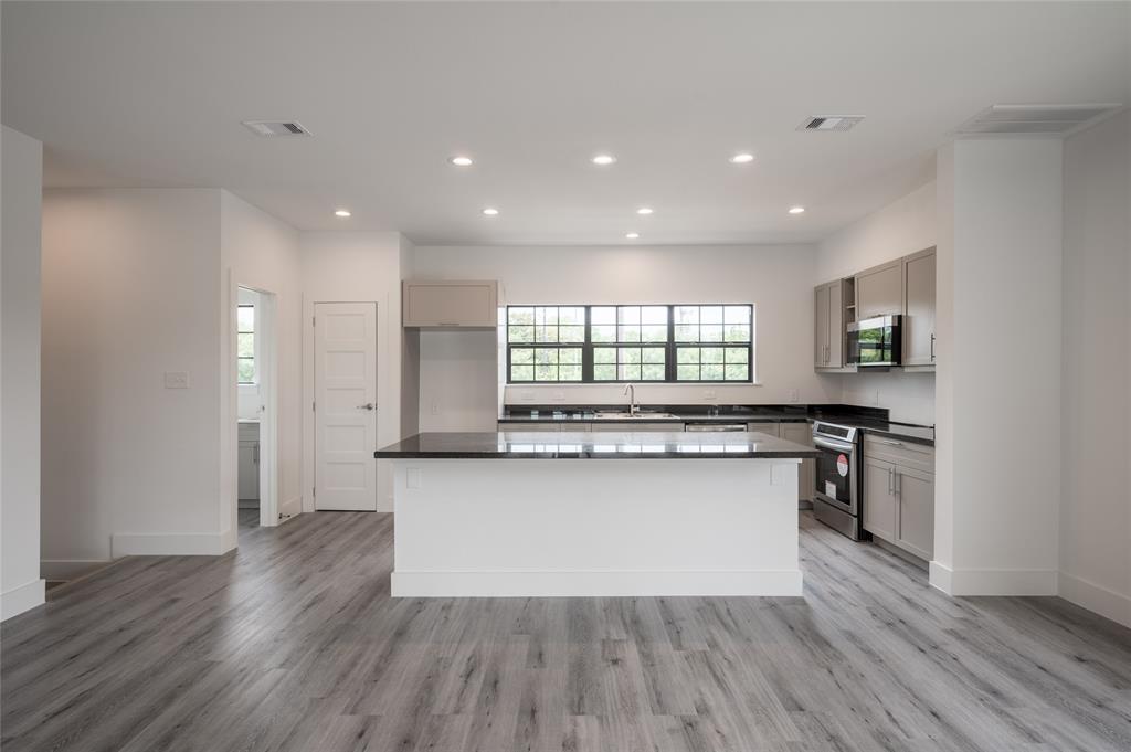 a kitchen with stainless steel appliances granite countertop wooden cabinets and wooden floor