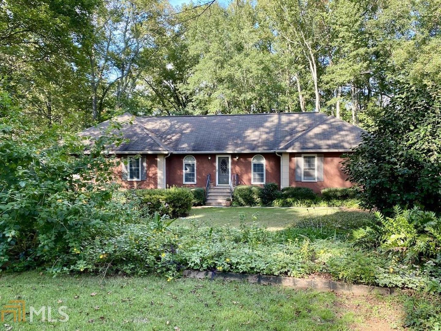 a view of a house with a yard plants and large tree