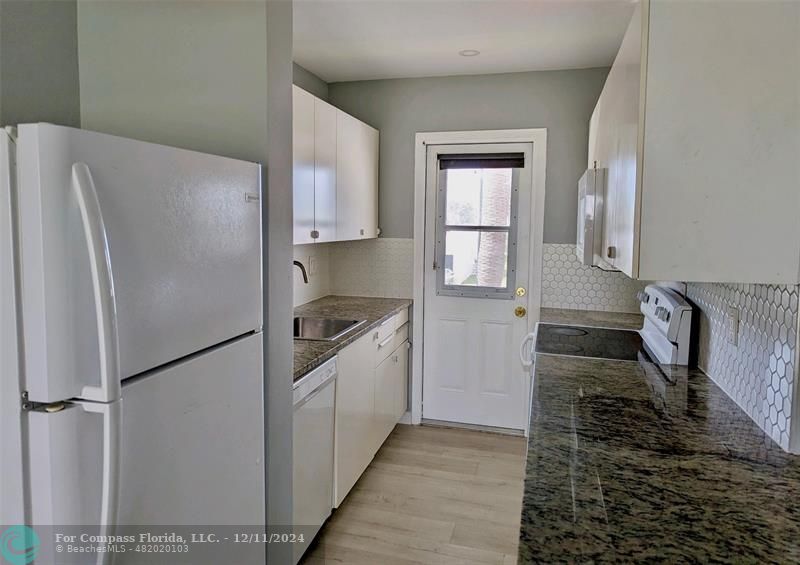 a kitchen with granite countertop a refrigerator and a sink