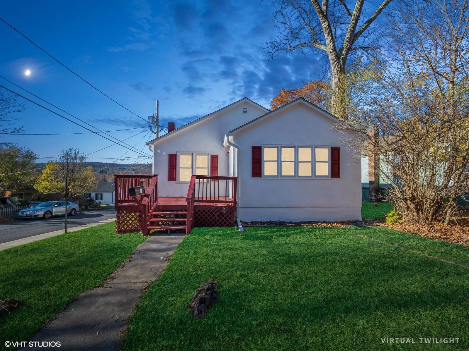 View of front of house with a deck and a front yard