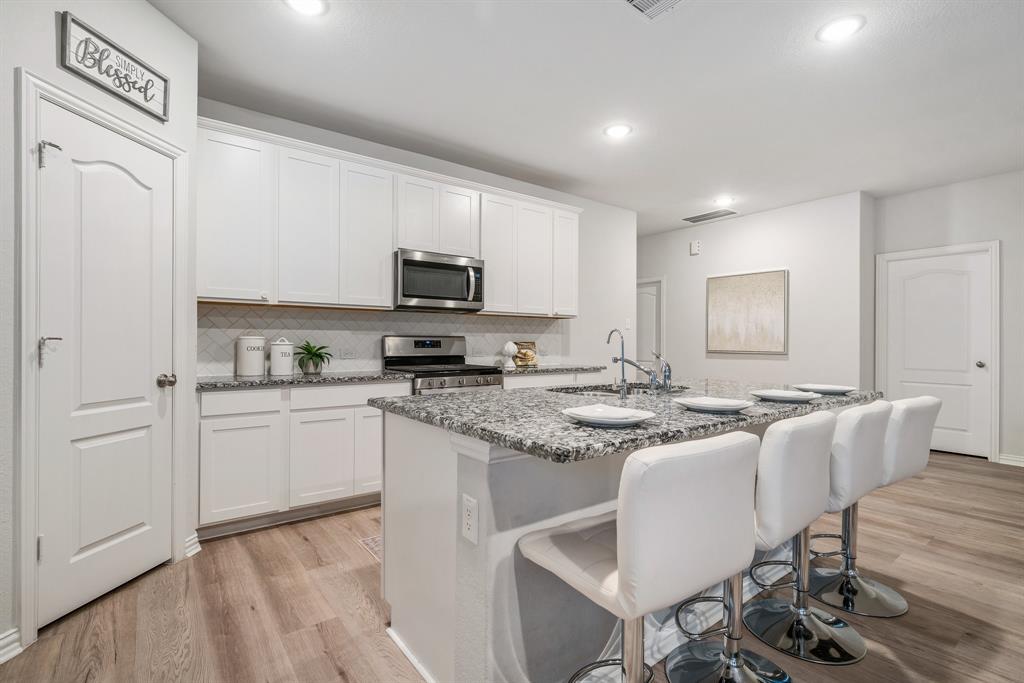 a kitchen with kitchen island granite countertop a sink cabinets and wooden floor