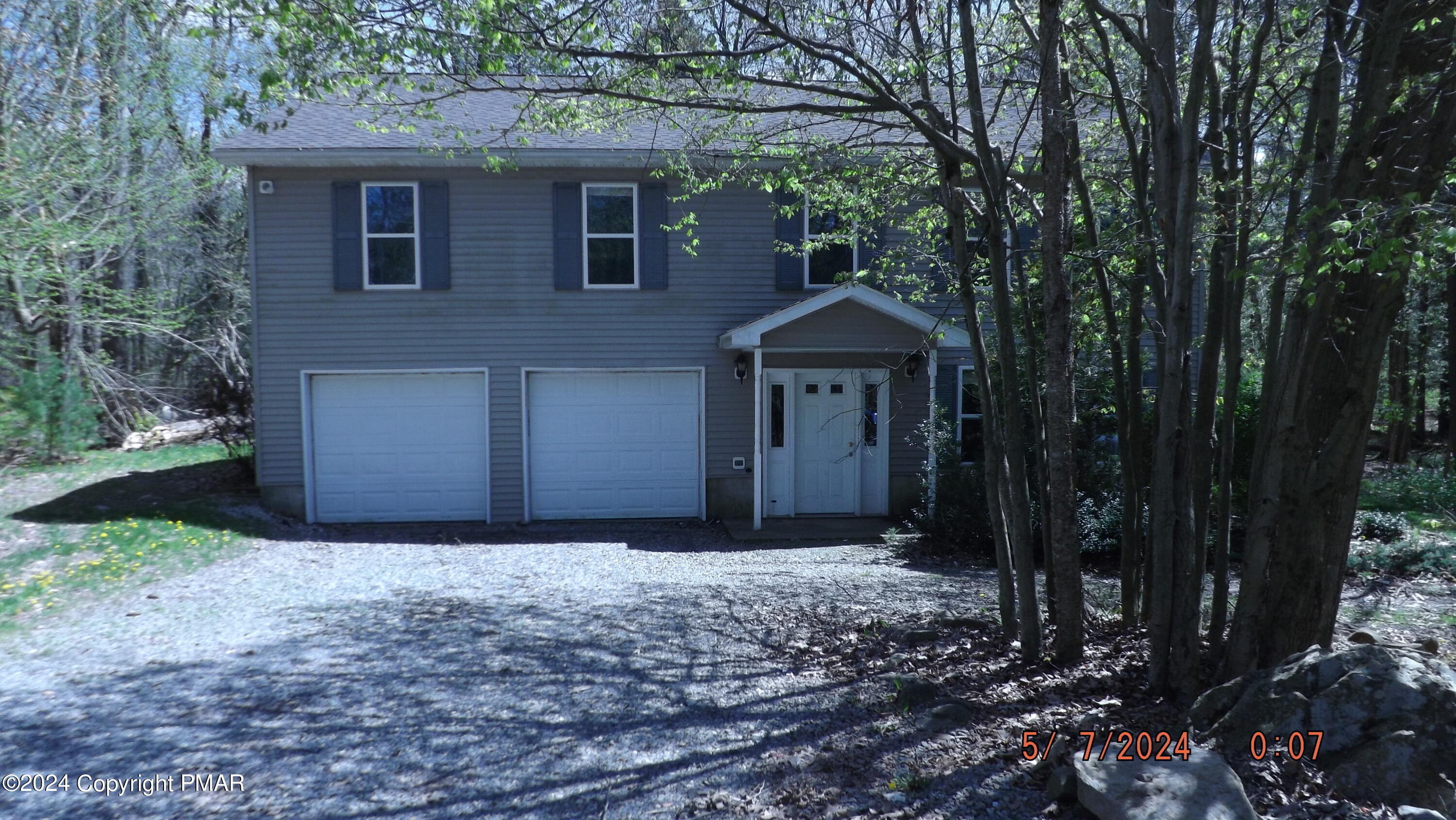 a front view of a house with a yard and large trees