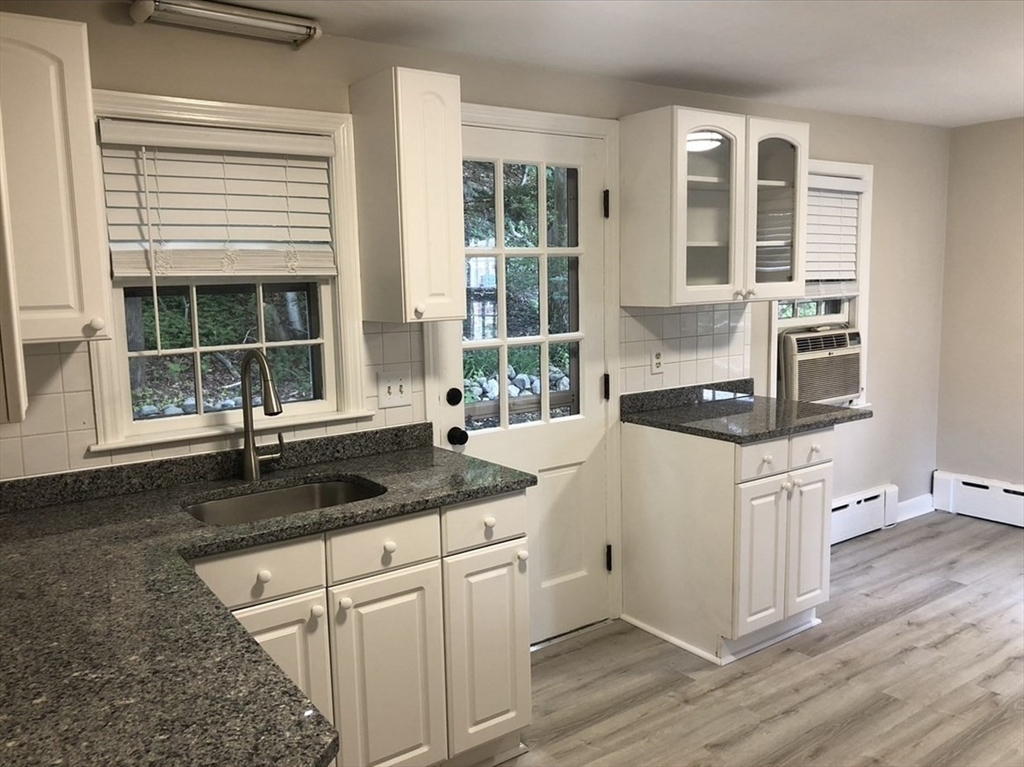 a kitchen with granite countertop a stove a sink and white cabinets