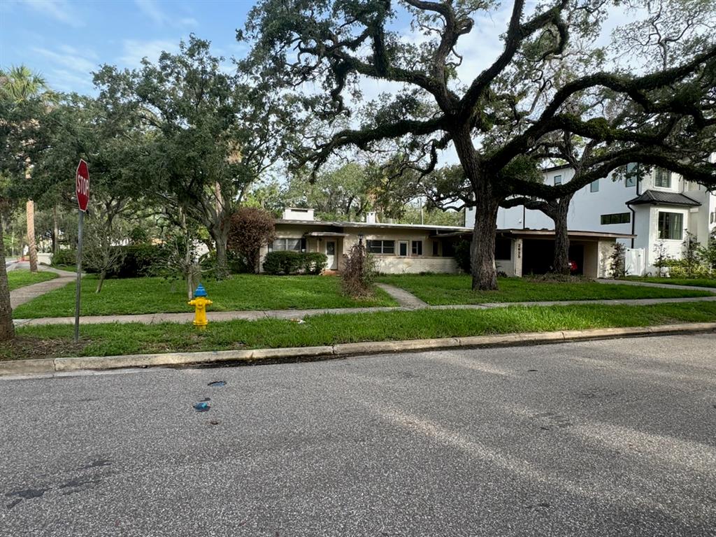 a view of a house with a big yard and large trees