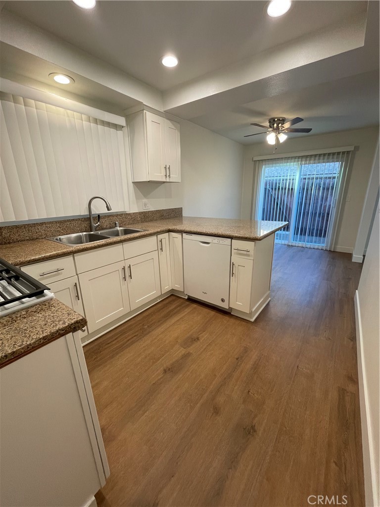 a kitchen with granite countertop a sink a stove cabinets and wooden floor