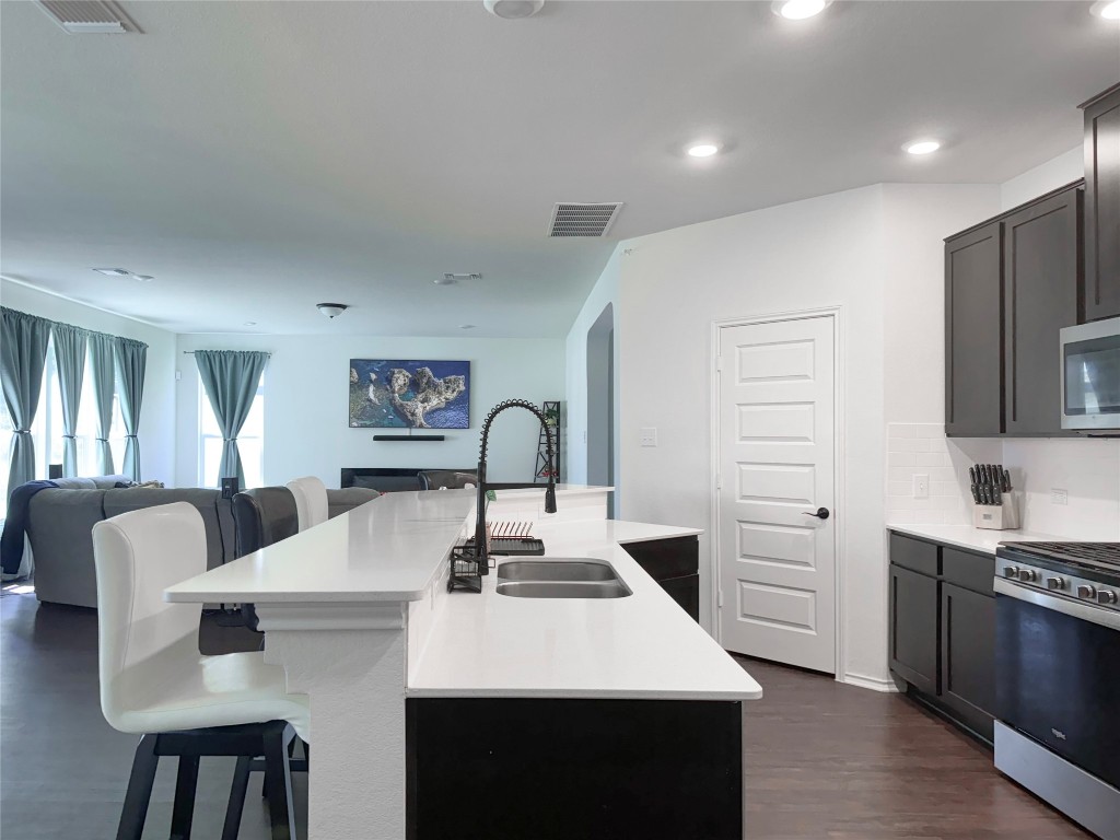 a kitchen with stainless steel appliances kitchen island a table chairs in it and wooden floors