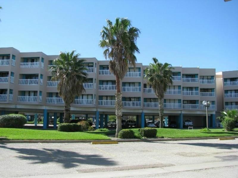 a front view of multi story residential apartment building with yard and sign board