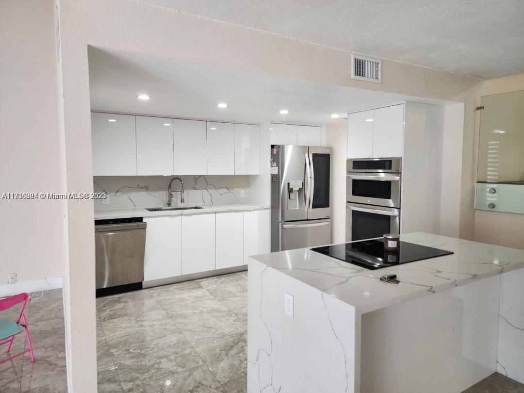 a kitchen with a refrigerator and a stove top oven