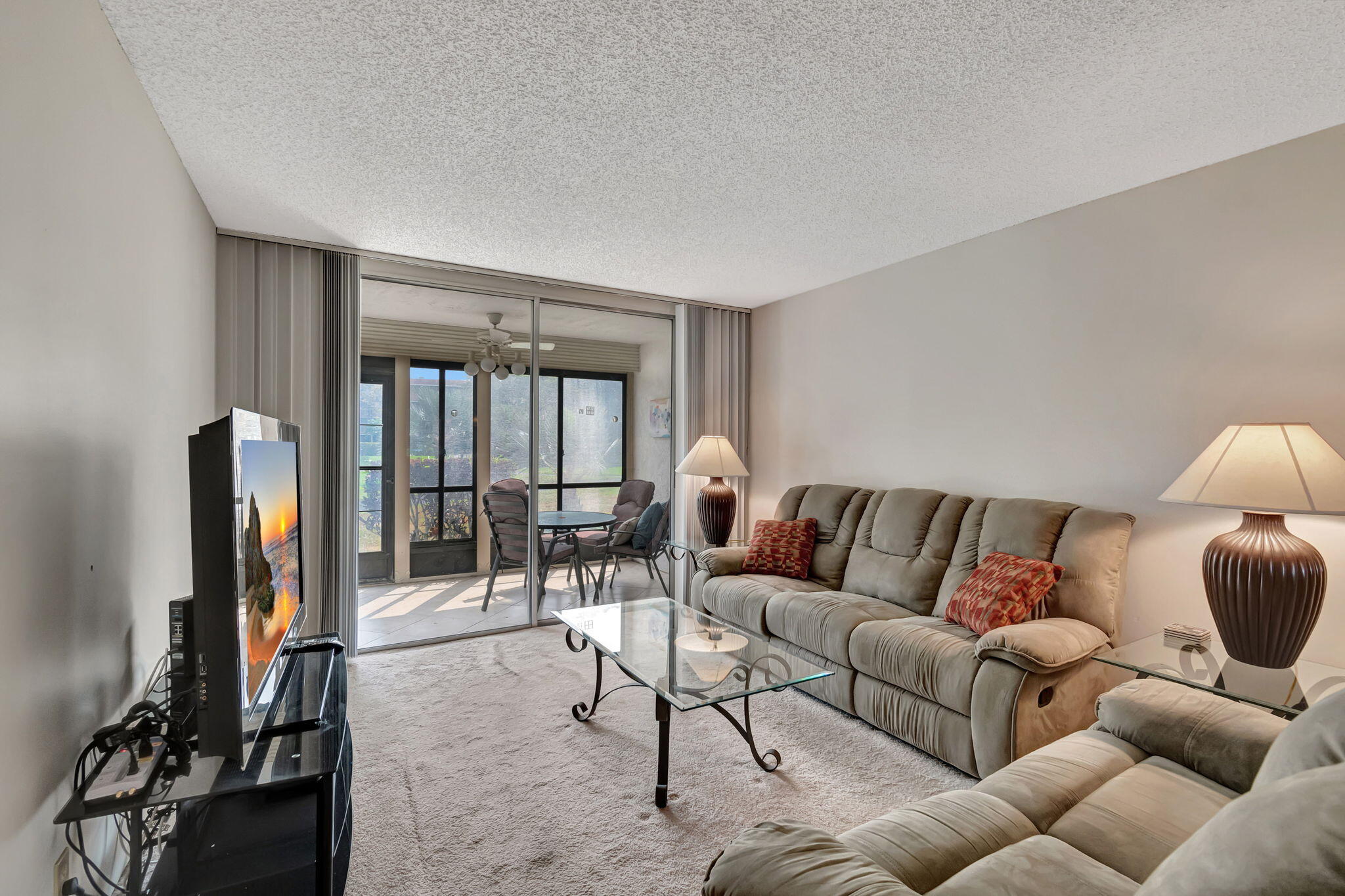 a living room with furniture a flat screen tv and a floor to ceiling window