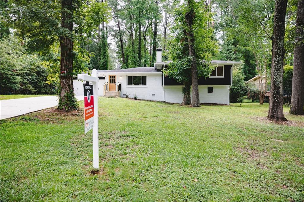 a front view of a house with a yard and tree