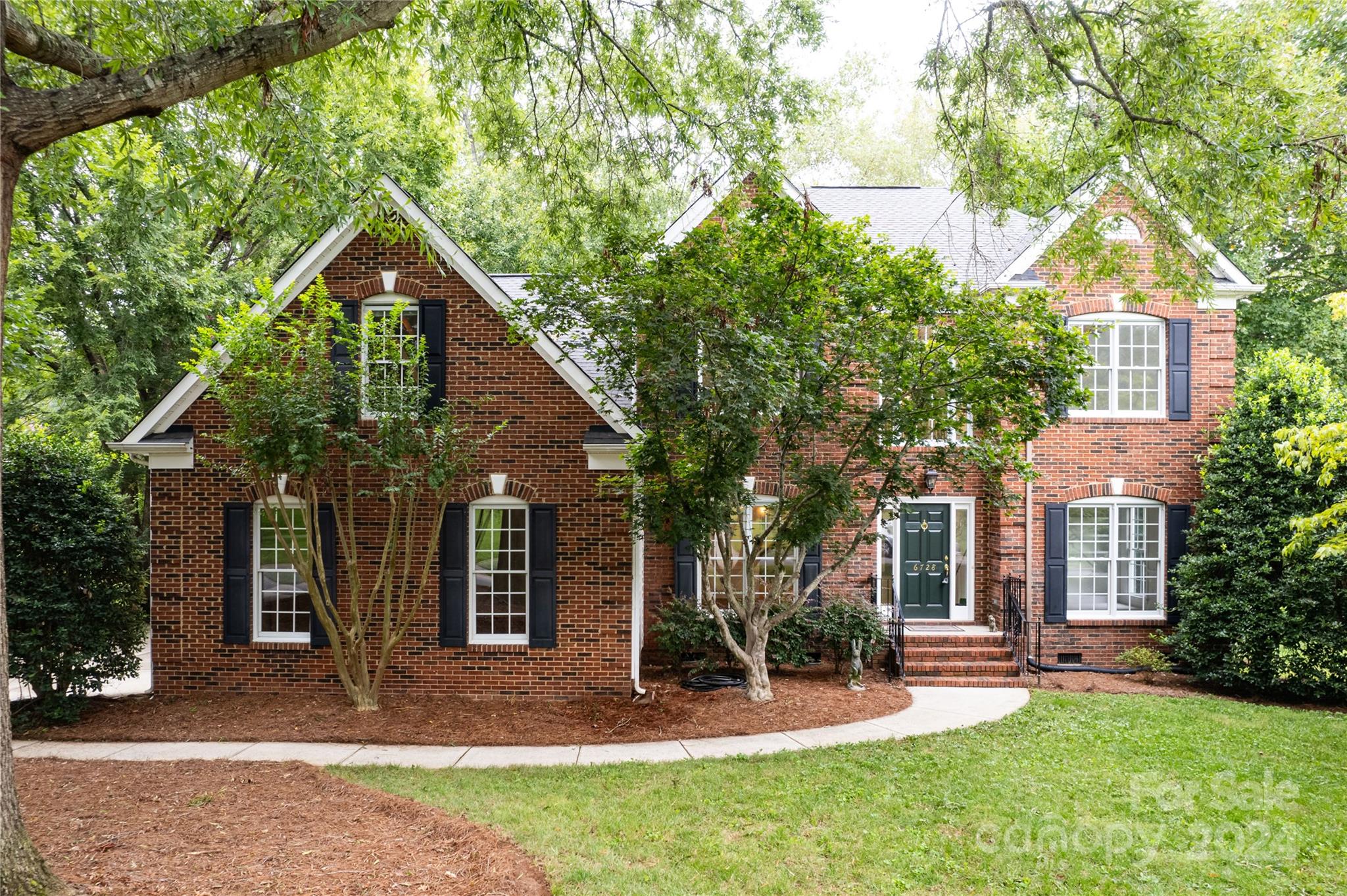 front view of a house with a yard and an trees