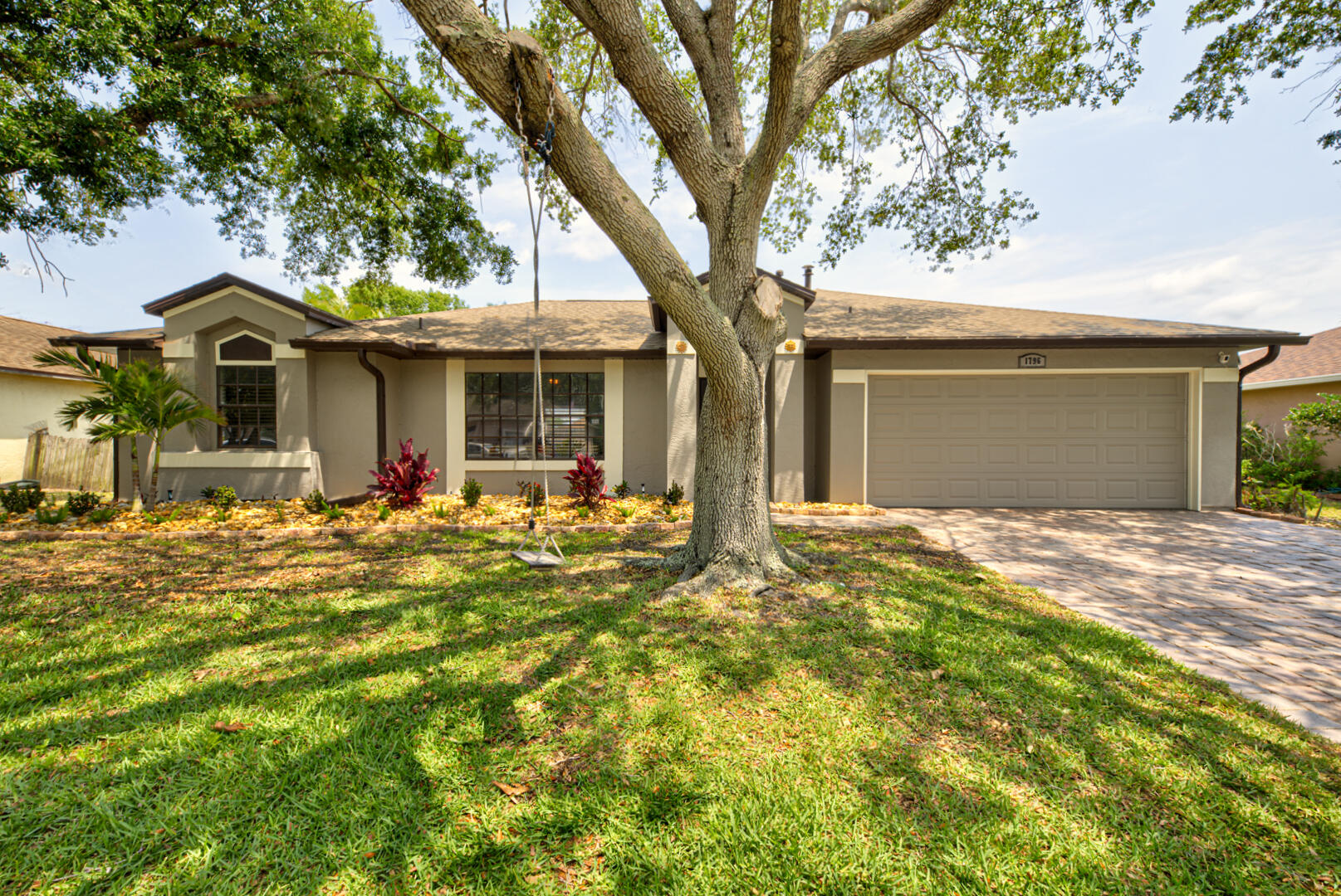 a view of a house with a yard and large tree