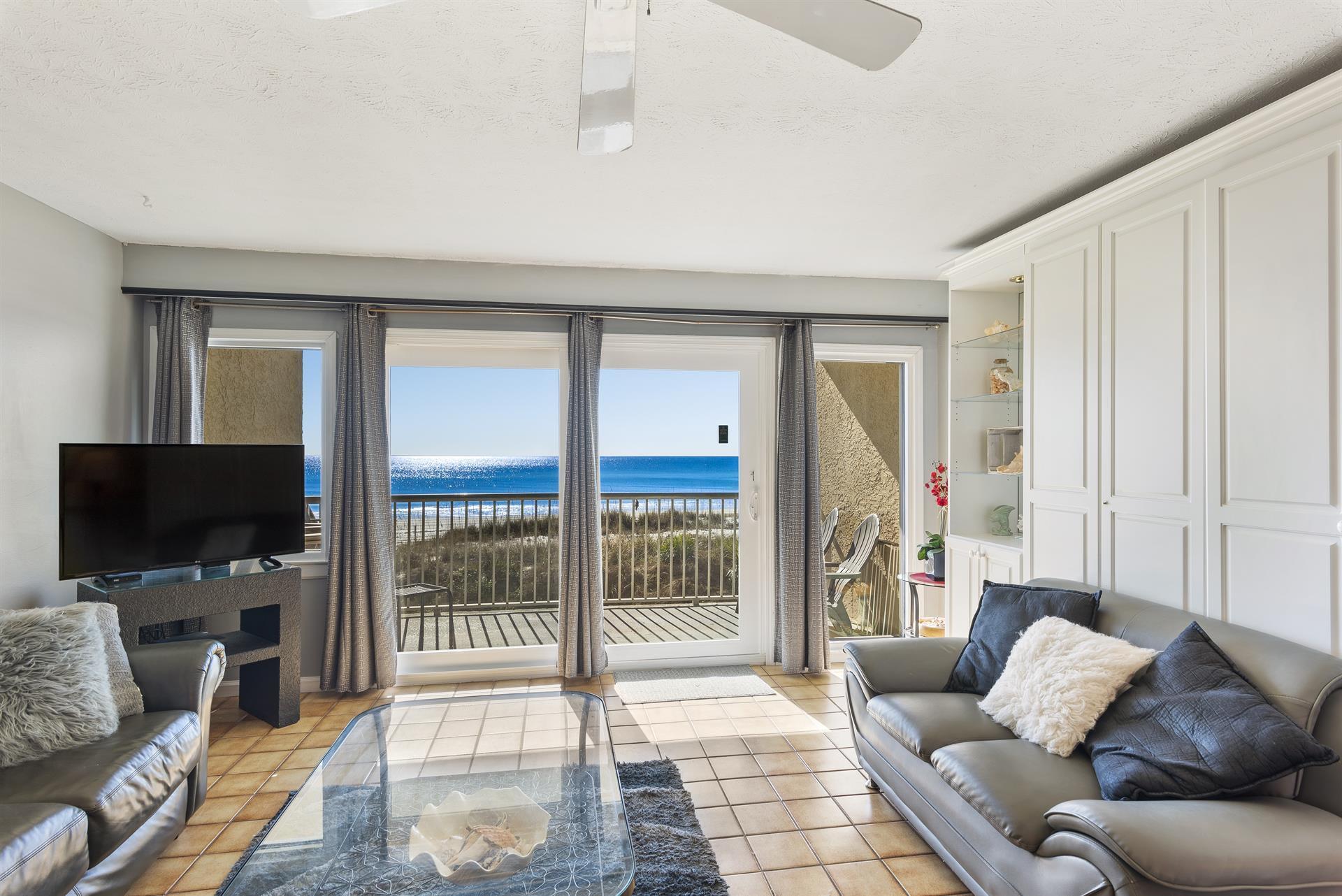 a living room with furniture a flat screen tv and a floor to ceiling window