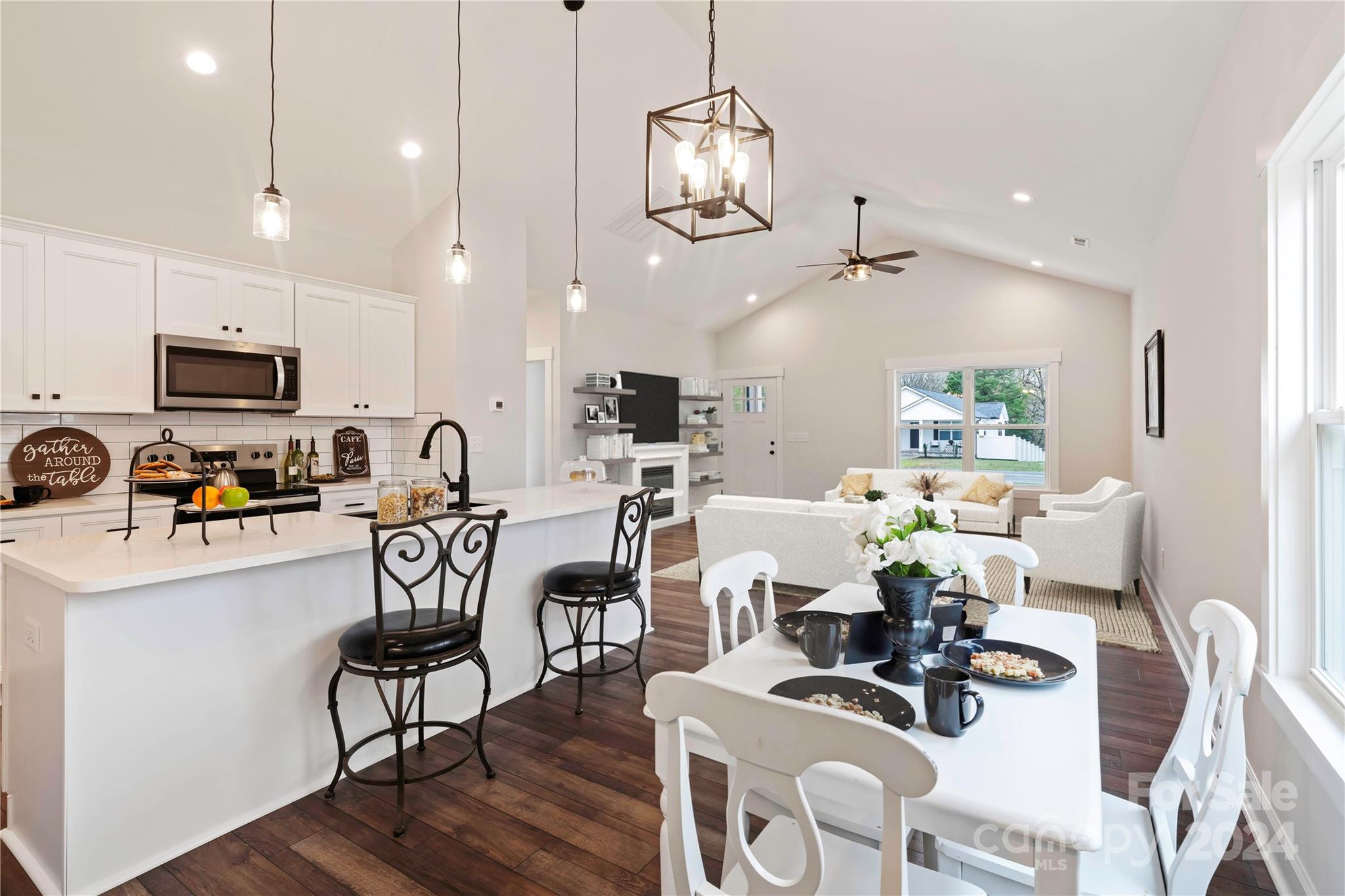 a kitchen with stainless steel appliances a dining table chairs stove top oven and sink