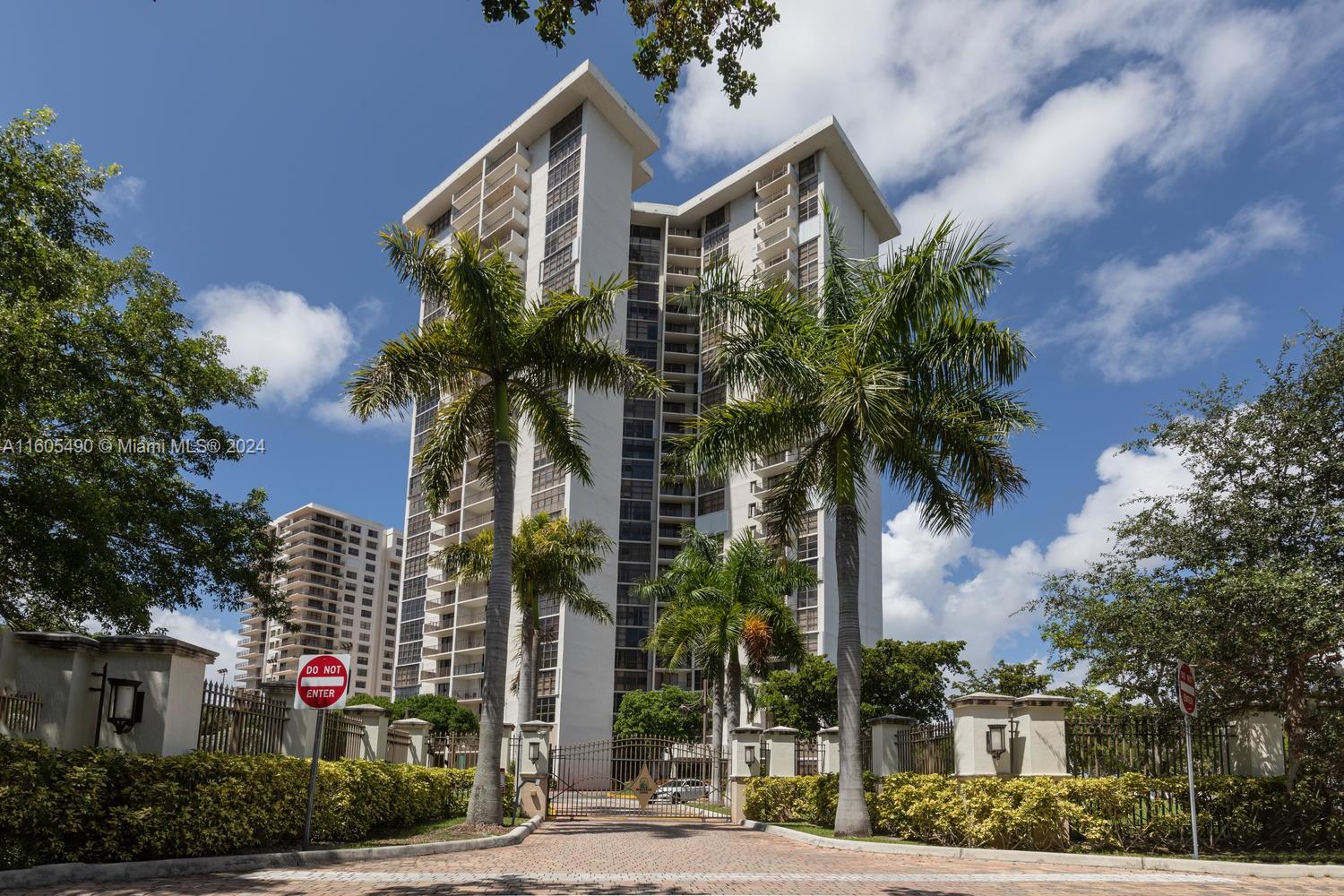 a front view of multi story residential apartment building with yard and sign board