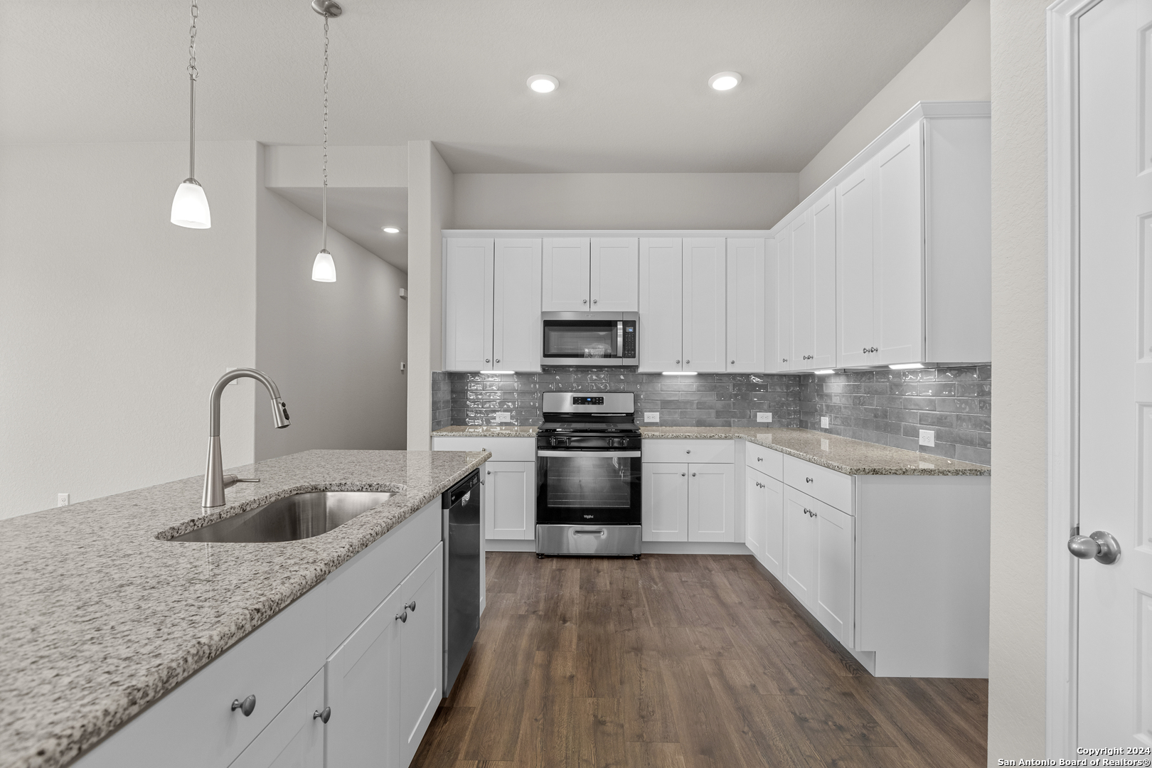 a kitchen with granite countertop a sink stainless steel appliances and white cabinets