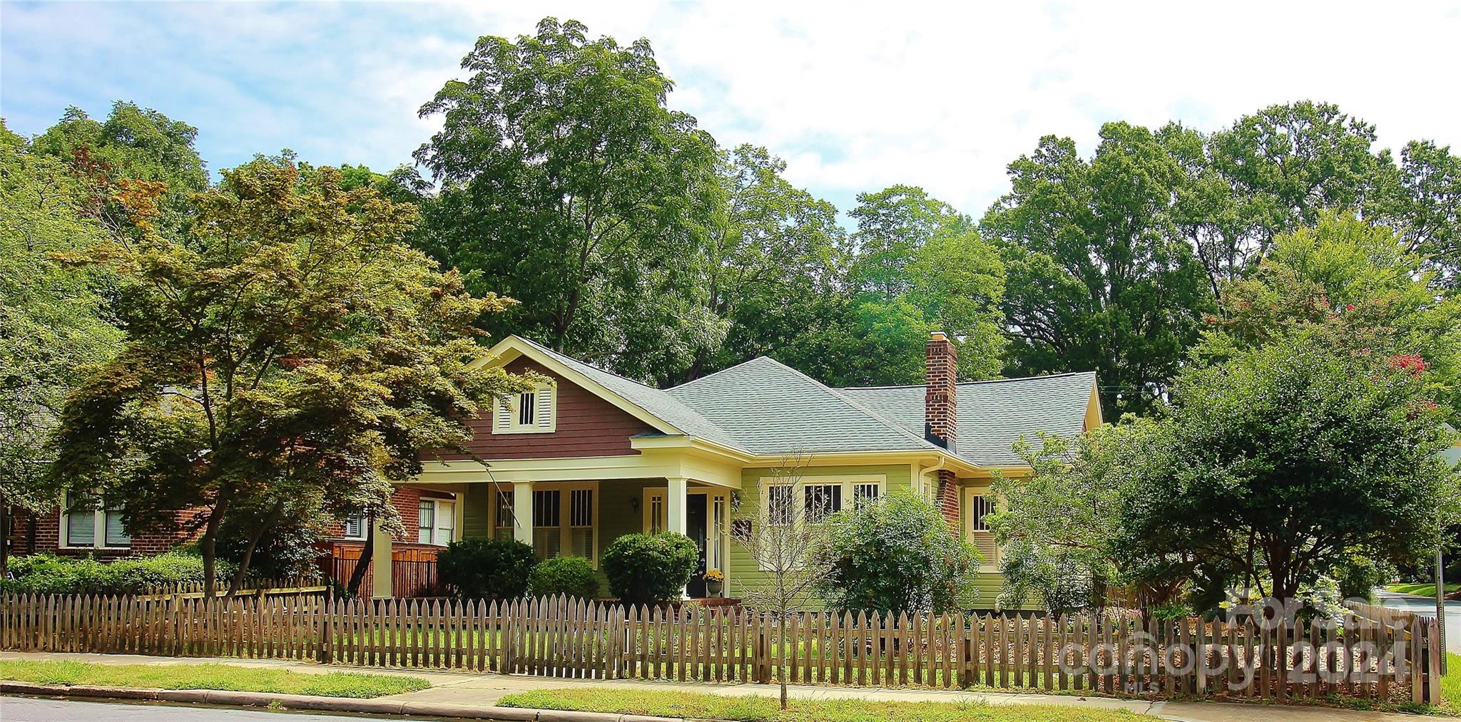 a view of a white house next to a yard with large trees