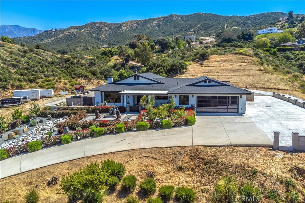 a front view of a house with a garden and mountain view