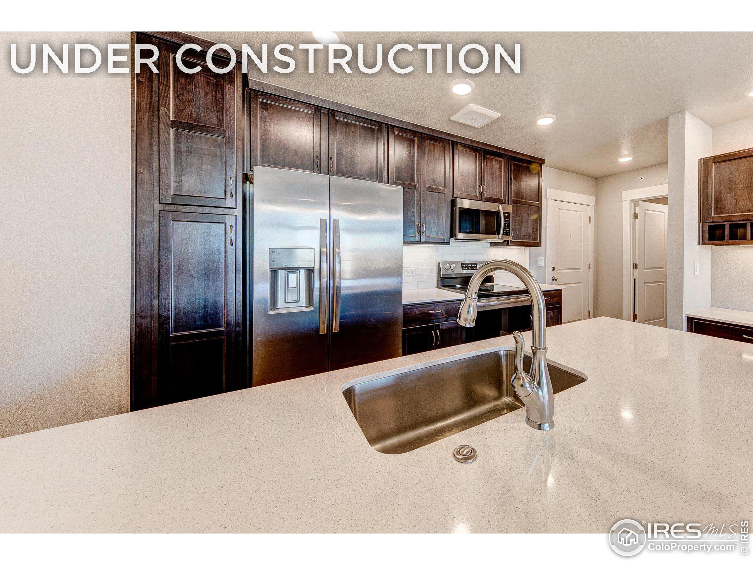 a kitchen with stainless steel appliances kitchen island granite countertop a refrigerator and a sink