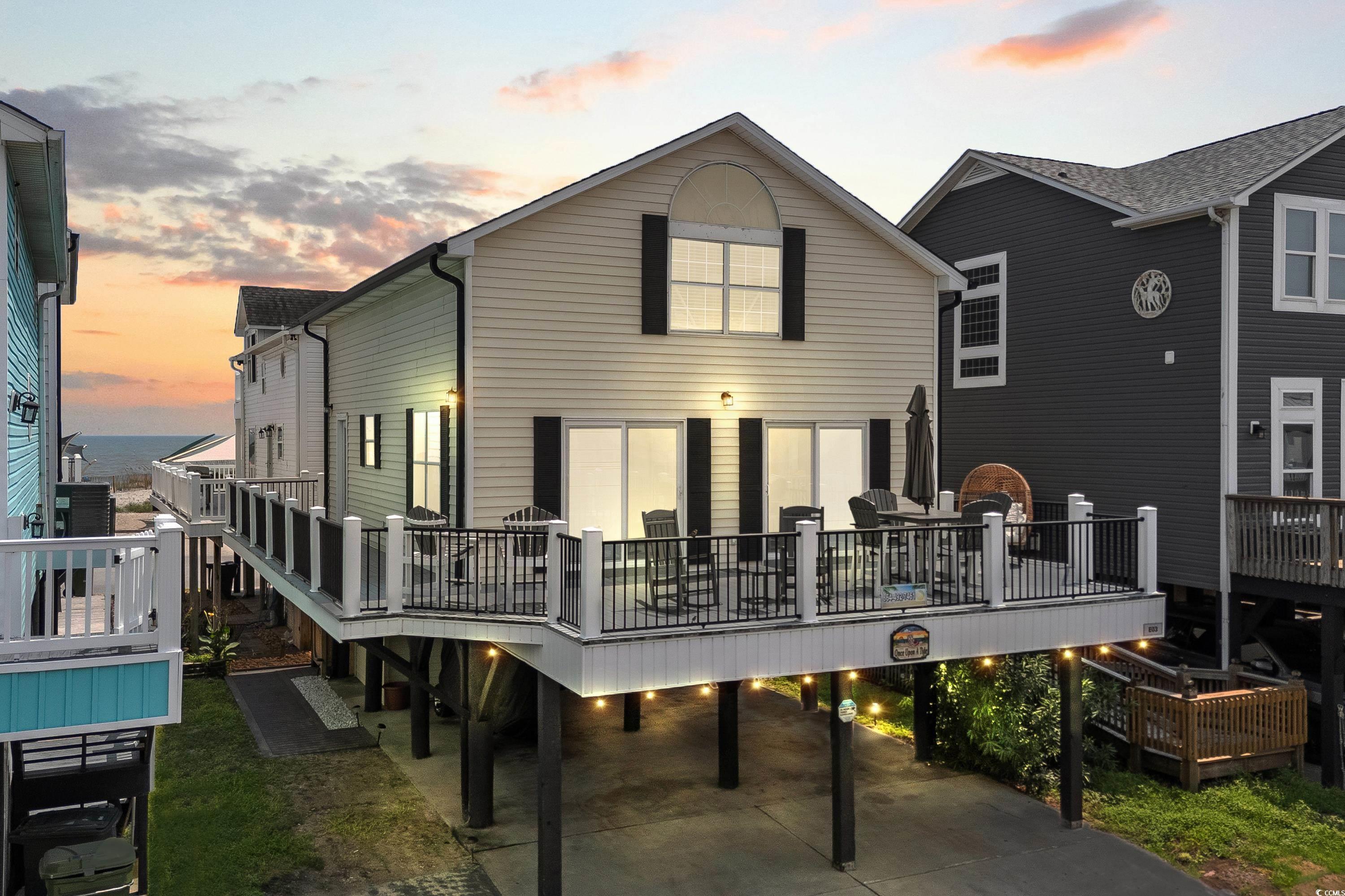 Back house at dusk featuring a deck with water vie