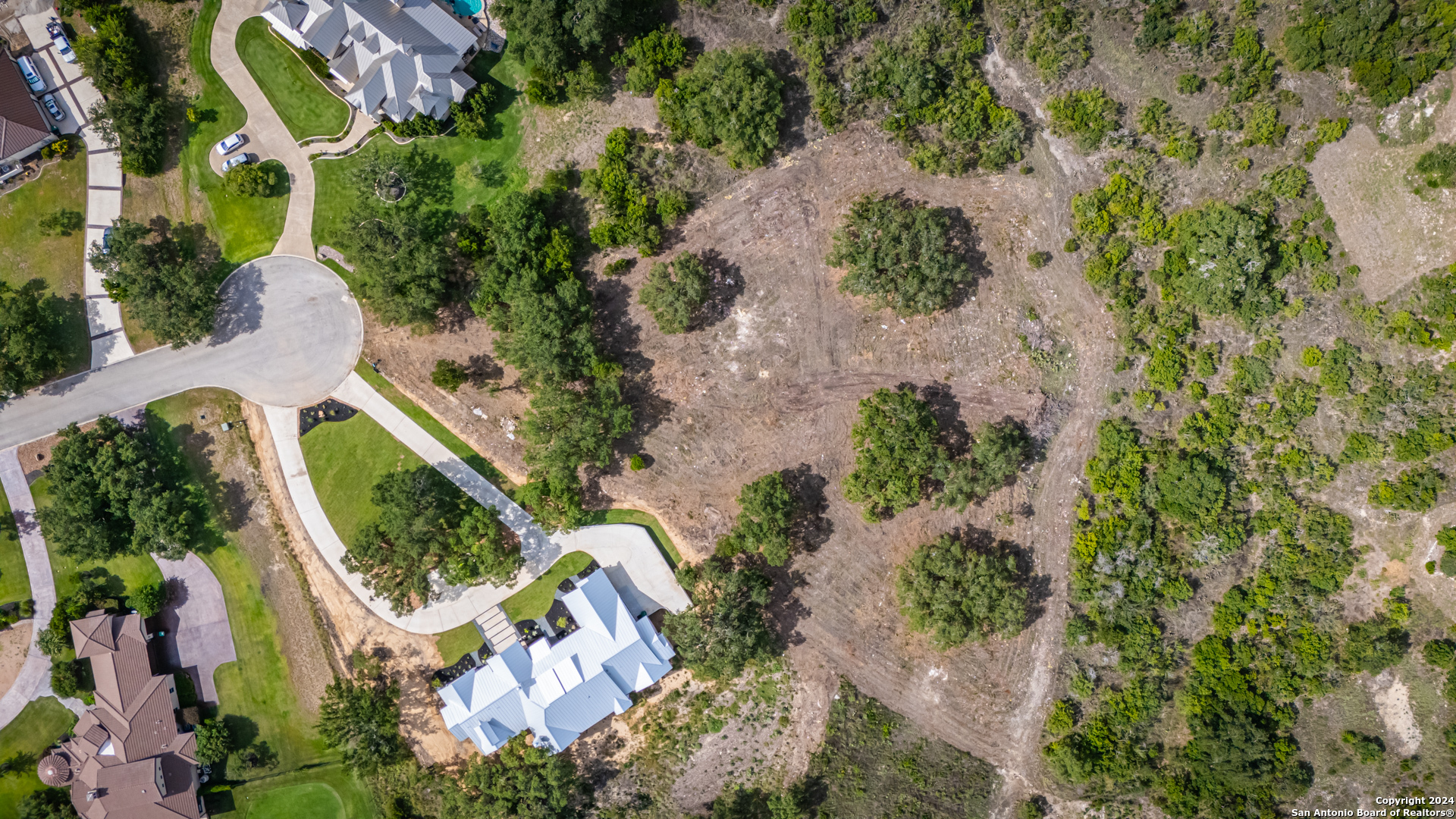 an aerial view of residential house with outdoor space and trees all around