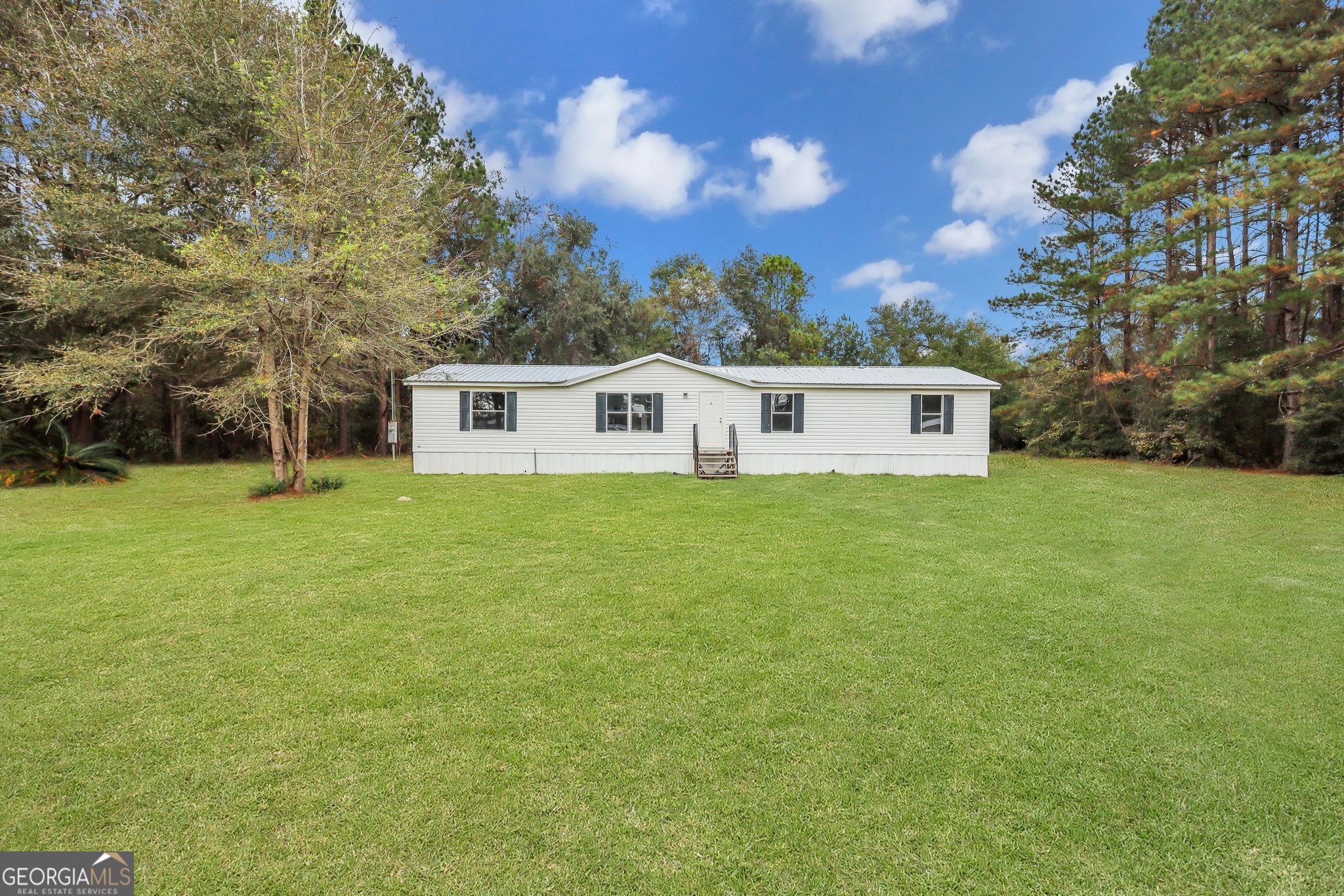 a view of house with yard and trees in the background