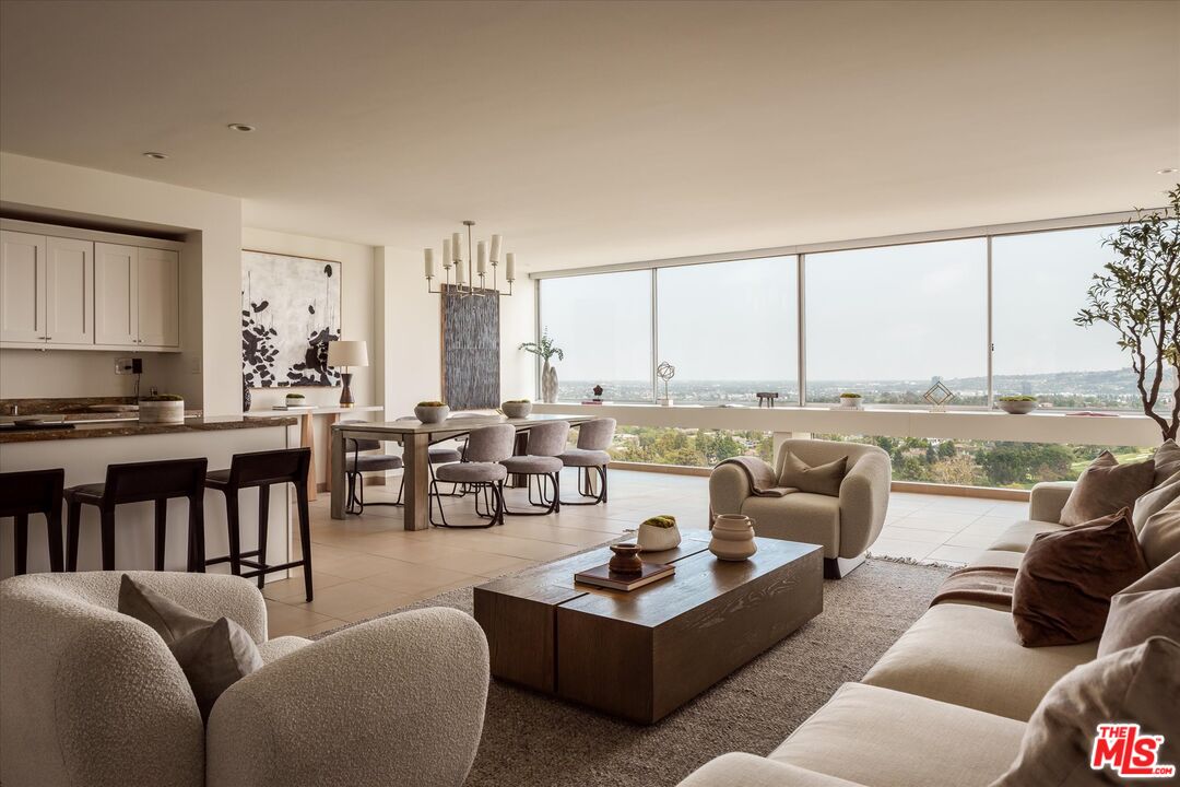 a living room with furniture kitchen view and large windows