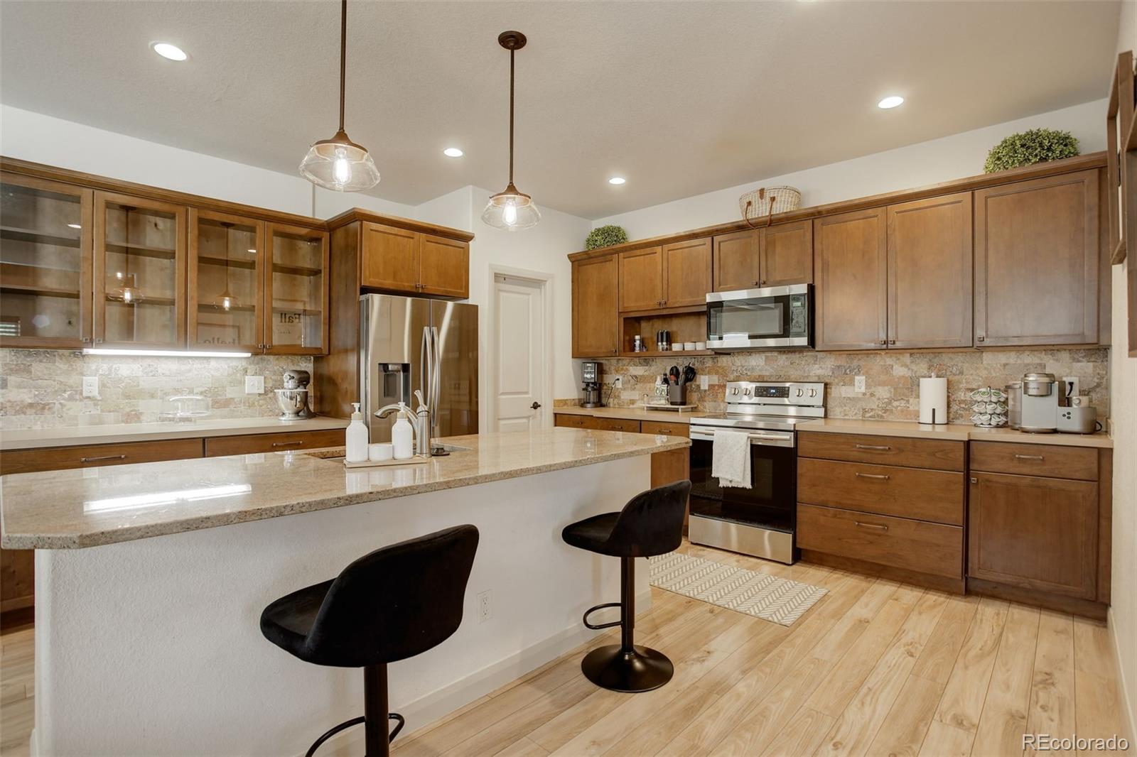 a kitchen with stainless steel appliances granite countertop a sink a stove a refrigerator cabinets and chairs