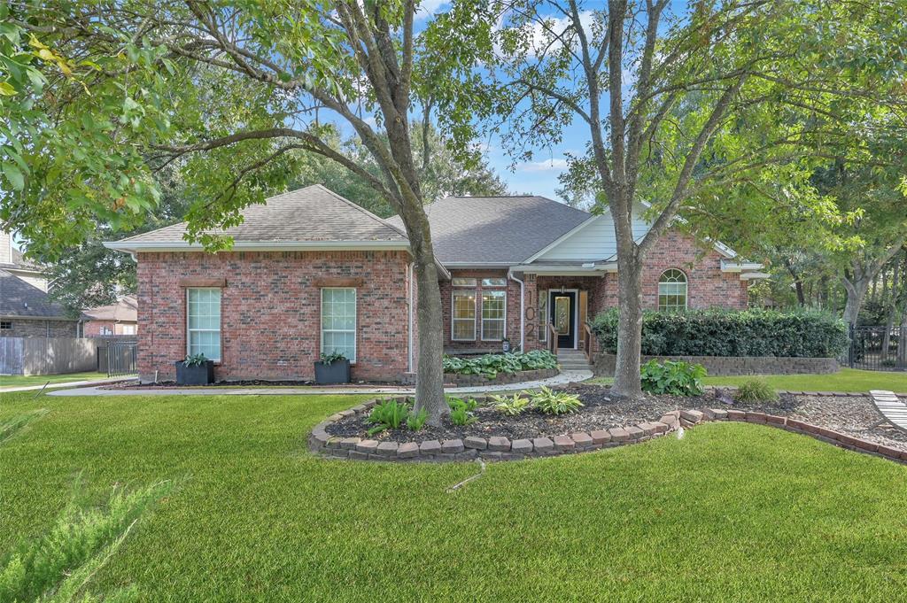 a view of a brick house with a yard and large trees