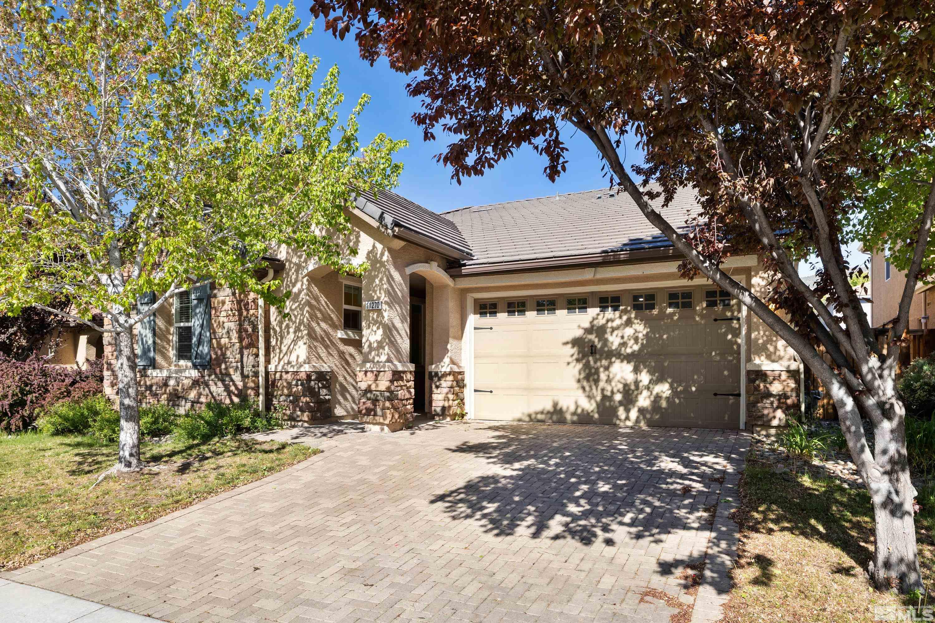 a front view of a house with a yard and tree