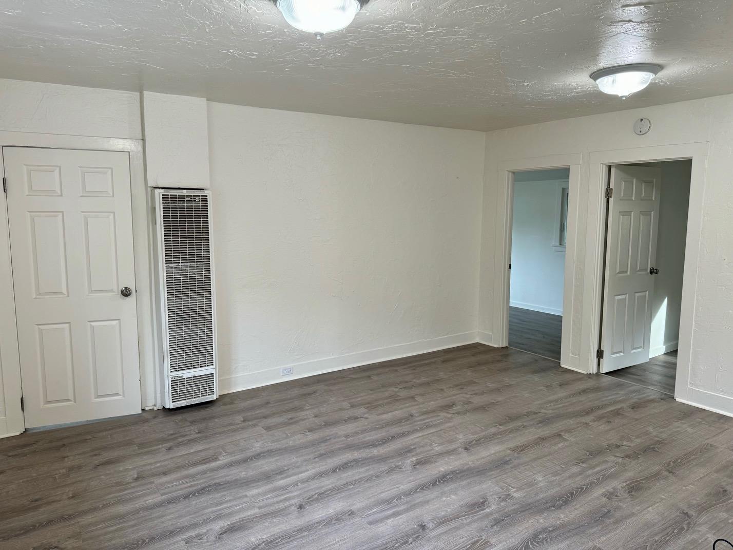 an empty room with wooden floor & closet area