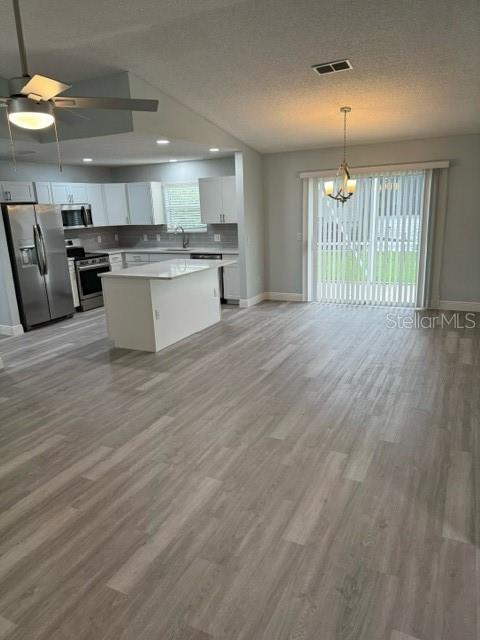 a large kitchen with stainless steel appliances kitchen island a large counter top and a wooden floors