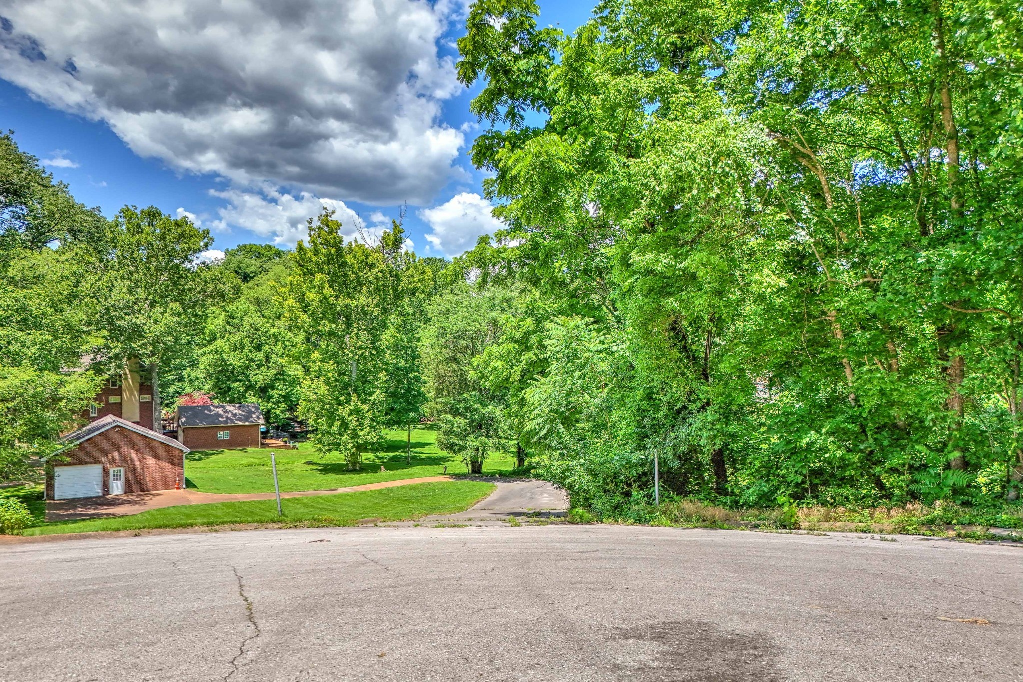 a view of a house with a big yard and large trees