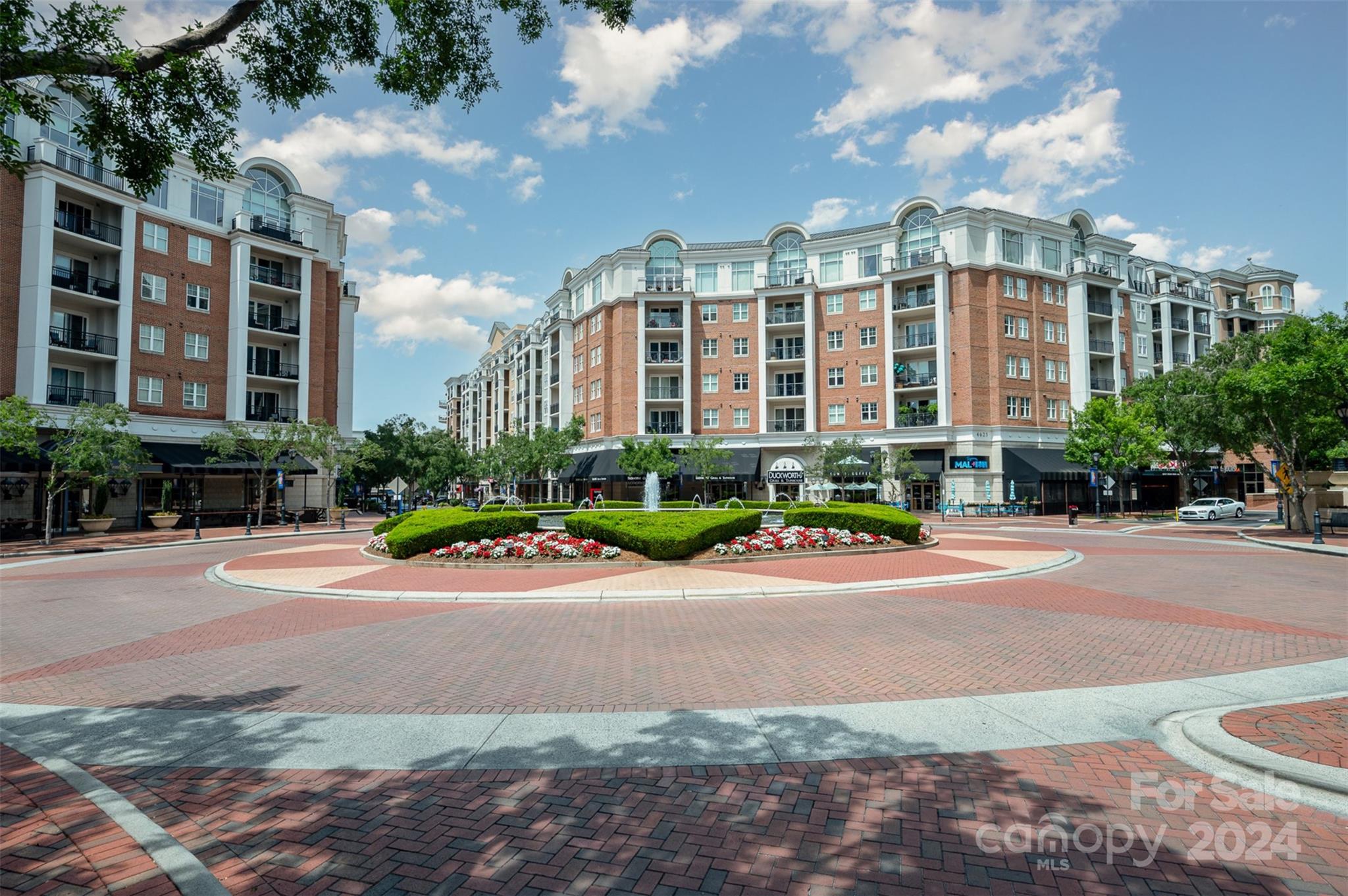 a front view of multi story residential apartment building with yard and outdoor seating