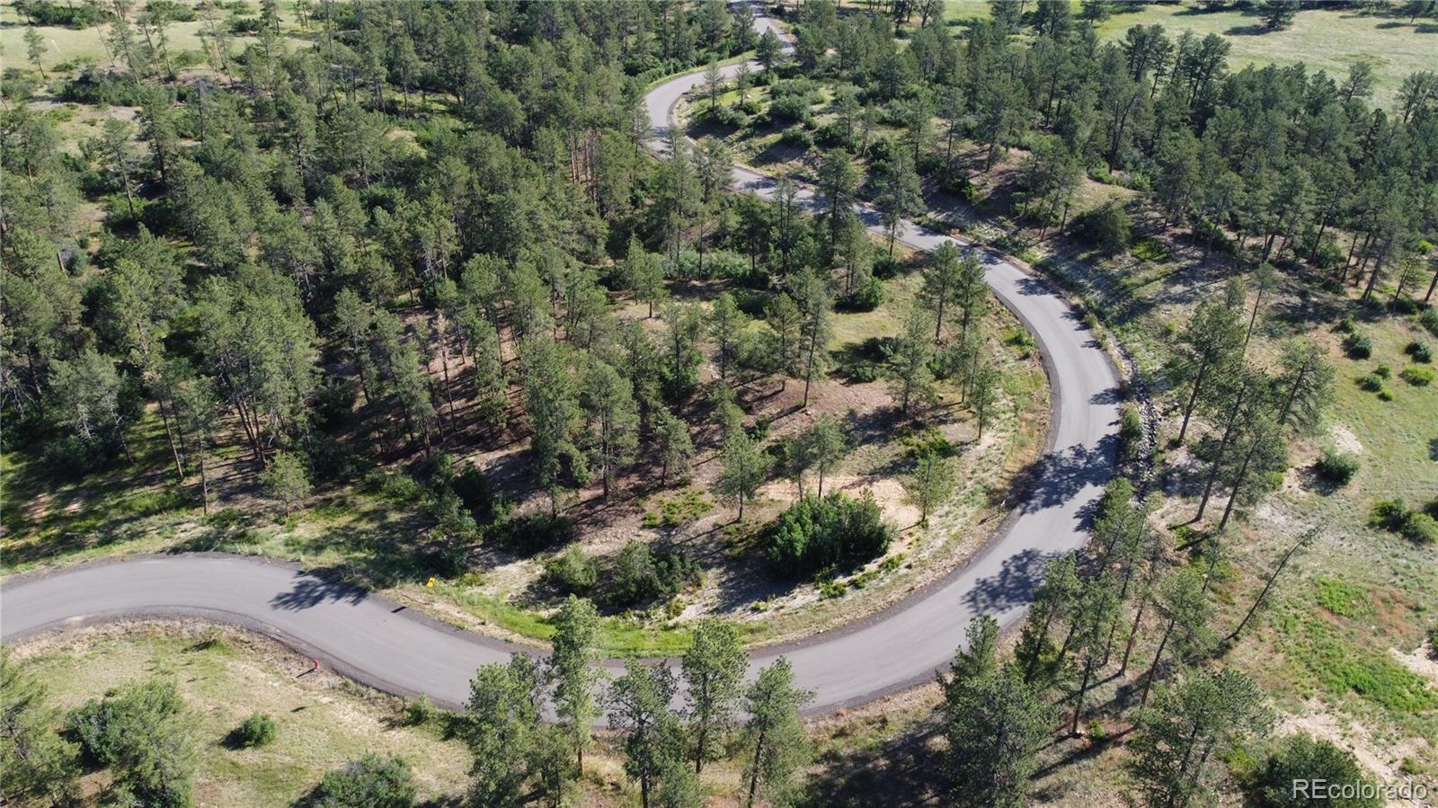 an aerial view of residential house with outdoor space and trees all around