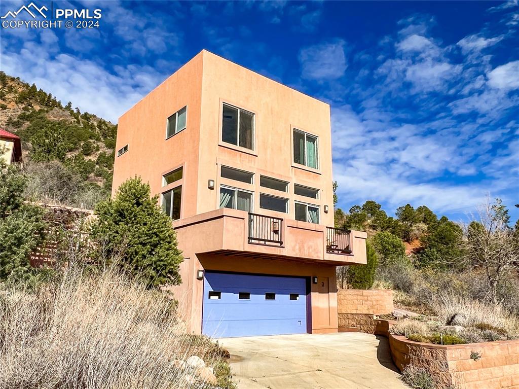 View of front of home featuring a garage and a balcony