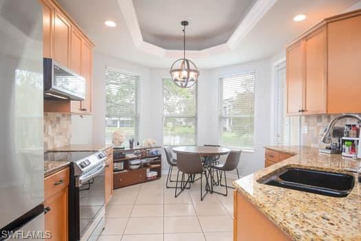 Kitchen with backsplash, sink, hanging light fixtures, a tray ceiling, and stainless steel appliances